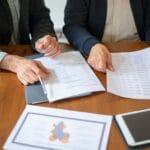 Dwóch przedsiębiorców analizuje dokumenty przetargowe przy biurku