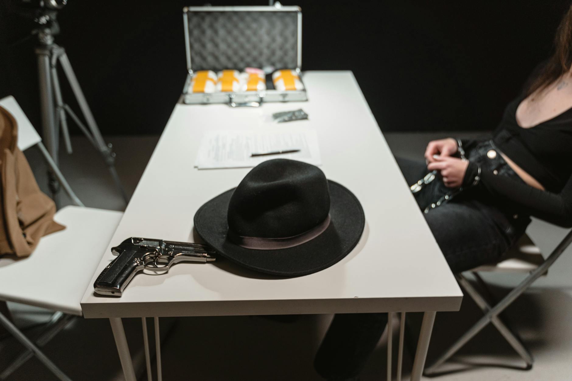 Pistolet i kapelusz na stole w pokoju przesłuchań sugerującym zbrodnię