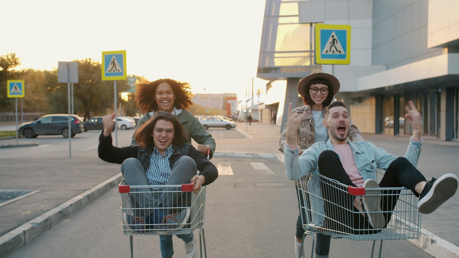 Grupa młodych przyjaciół pchających wózki sklepowe po miejskim chodniku