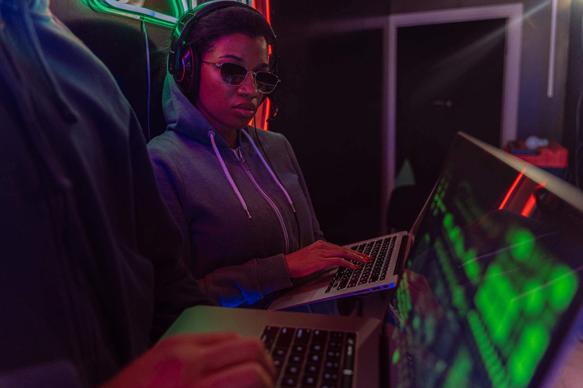 Osoba przy laptopie nocą w neonowym świetle o cyberpunkowym klimacie