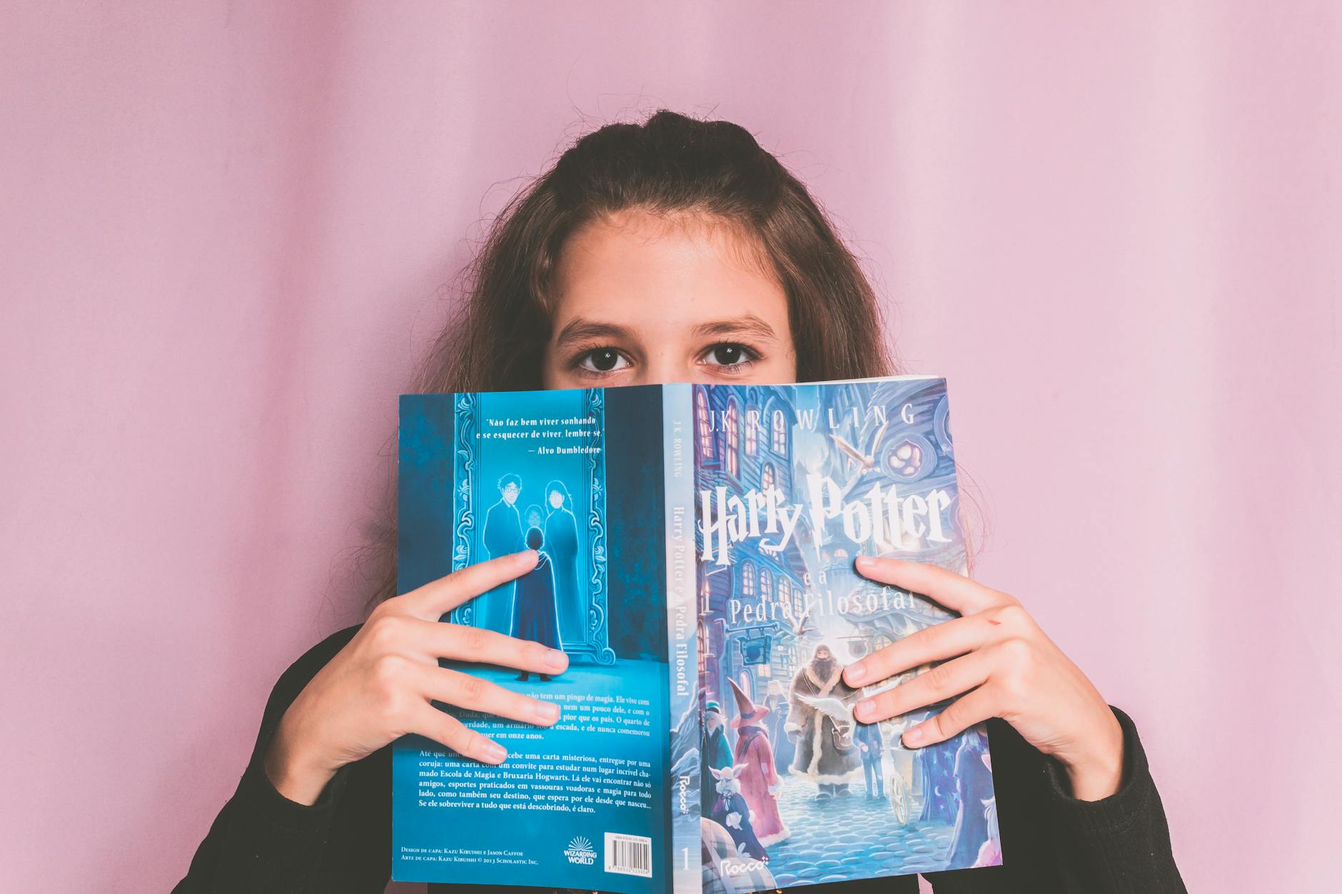Dziewczynka z książką Harry Potter na różowym tle