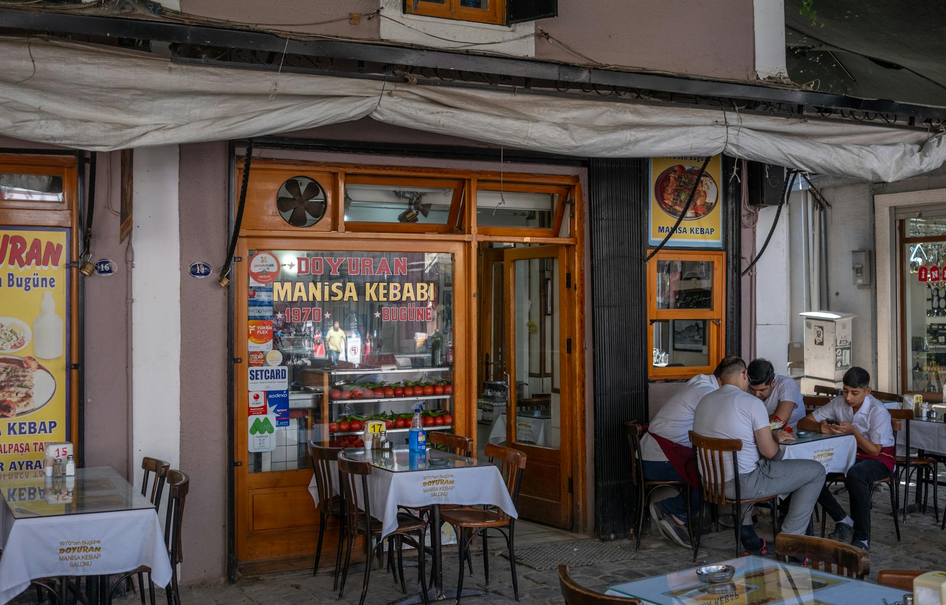 Ludzie jedzą kebab przy stolikach na ruchliwej ulicy wieczorem
