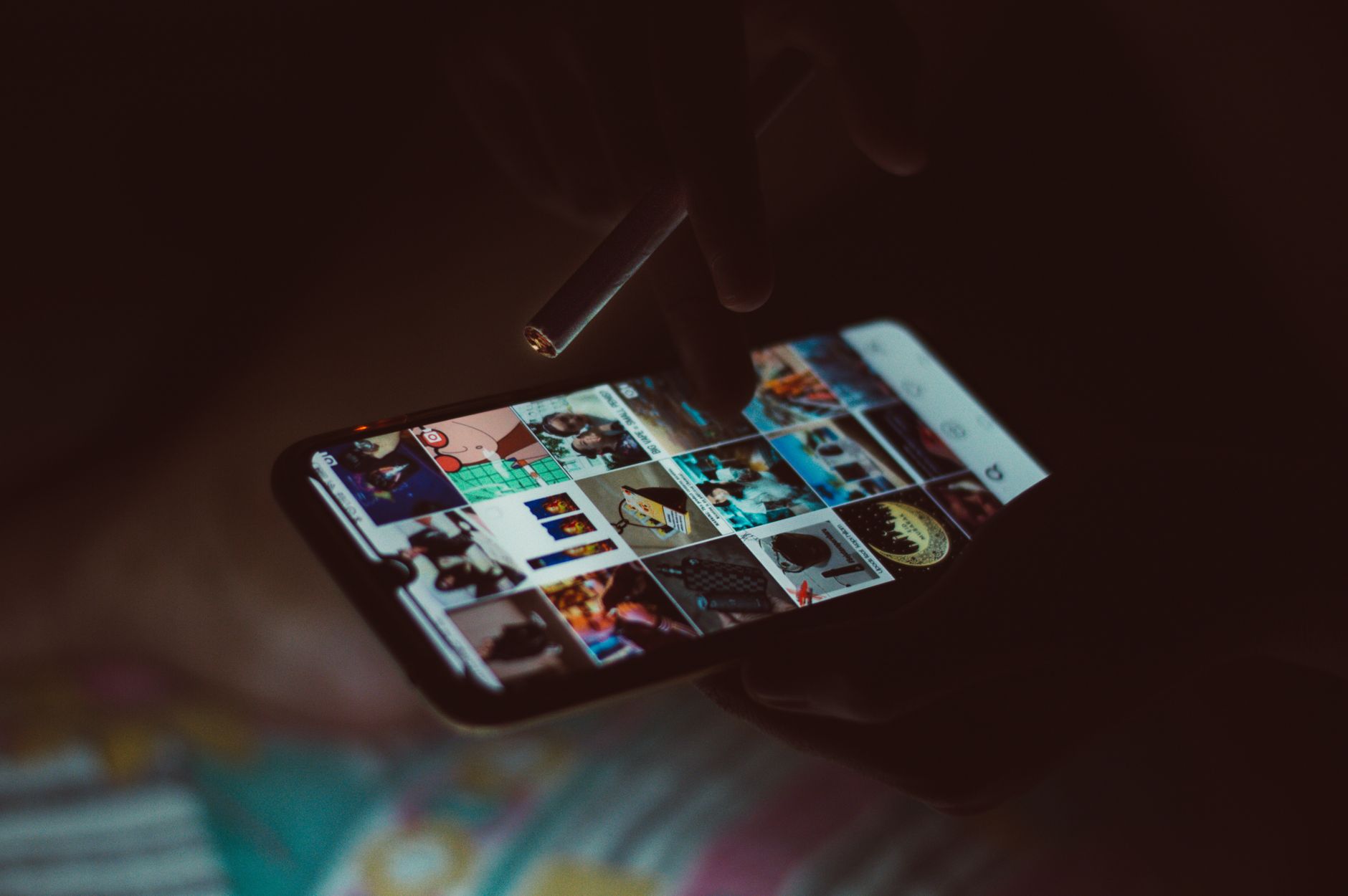 Dłoń z papierosem przeglądająca zdjęcia na smartfonie