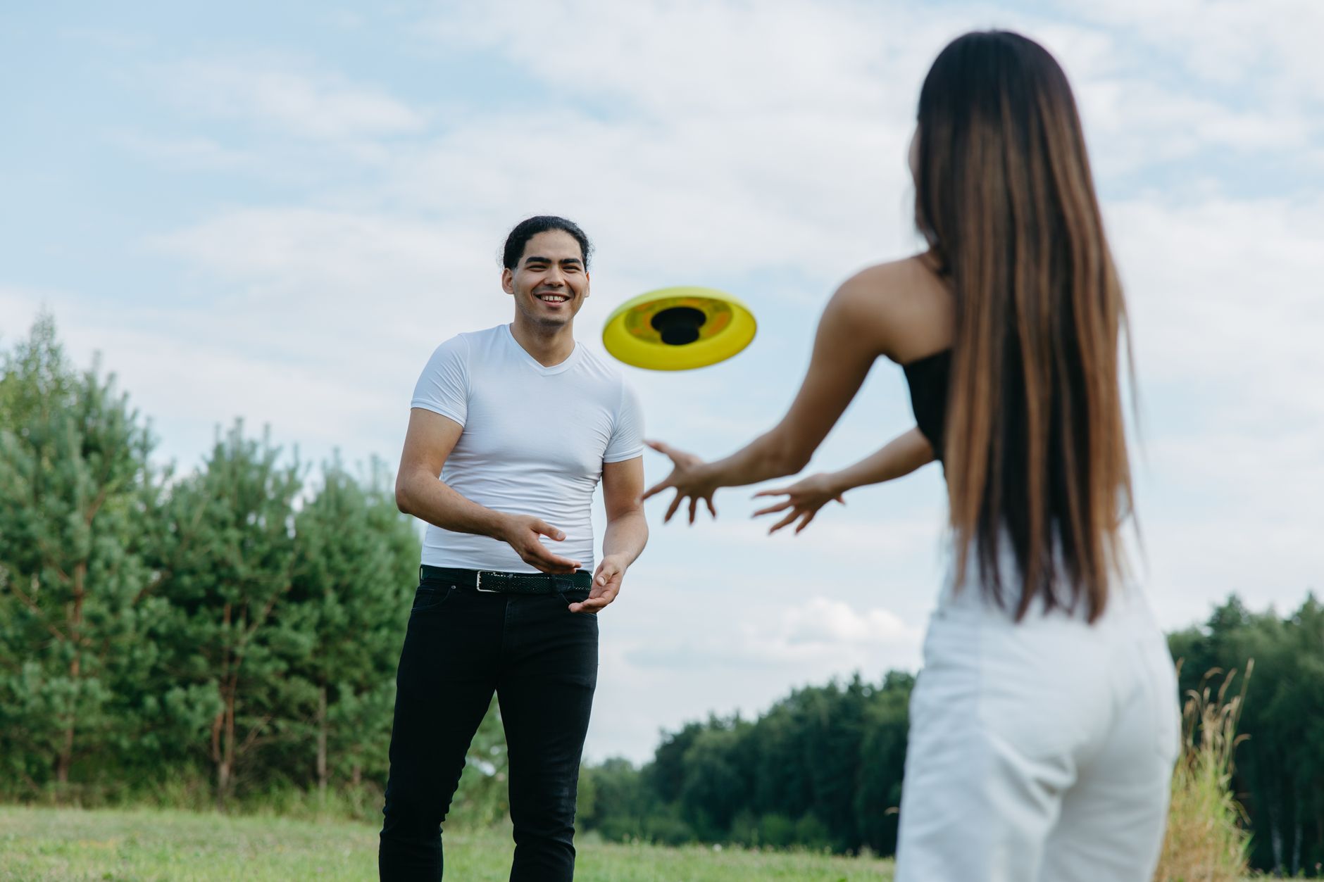 Para rzucająca frisbee w zielonym parku miejskim