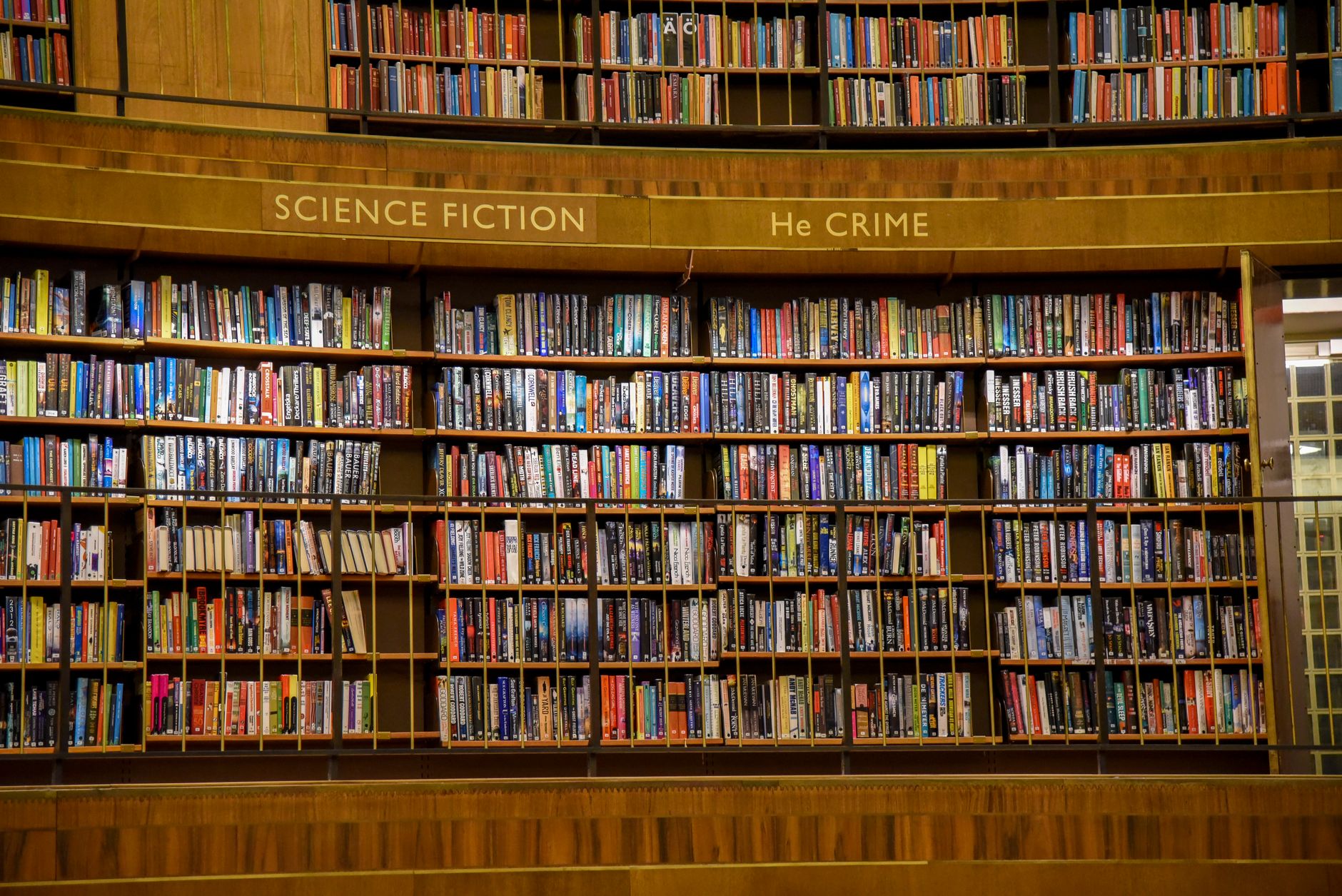 Wnętrze miejskiej biblioteki z drewnianymi regałami pełnymi kolorowych książek