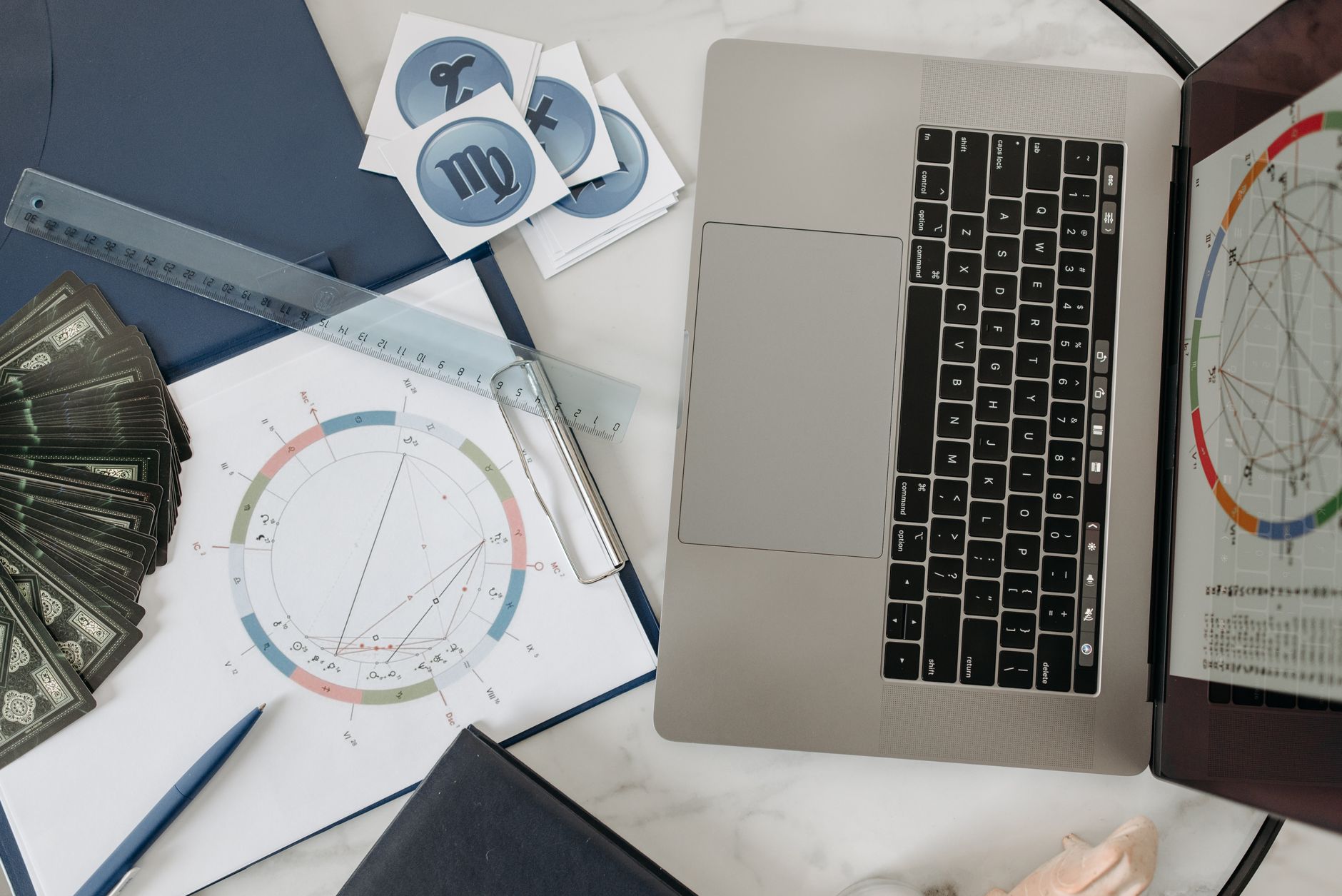 Wykres astrologiczny, laptop i karty tarota na biurku podczas analizy